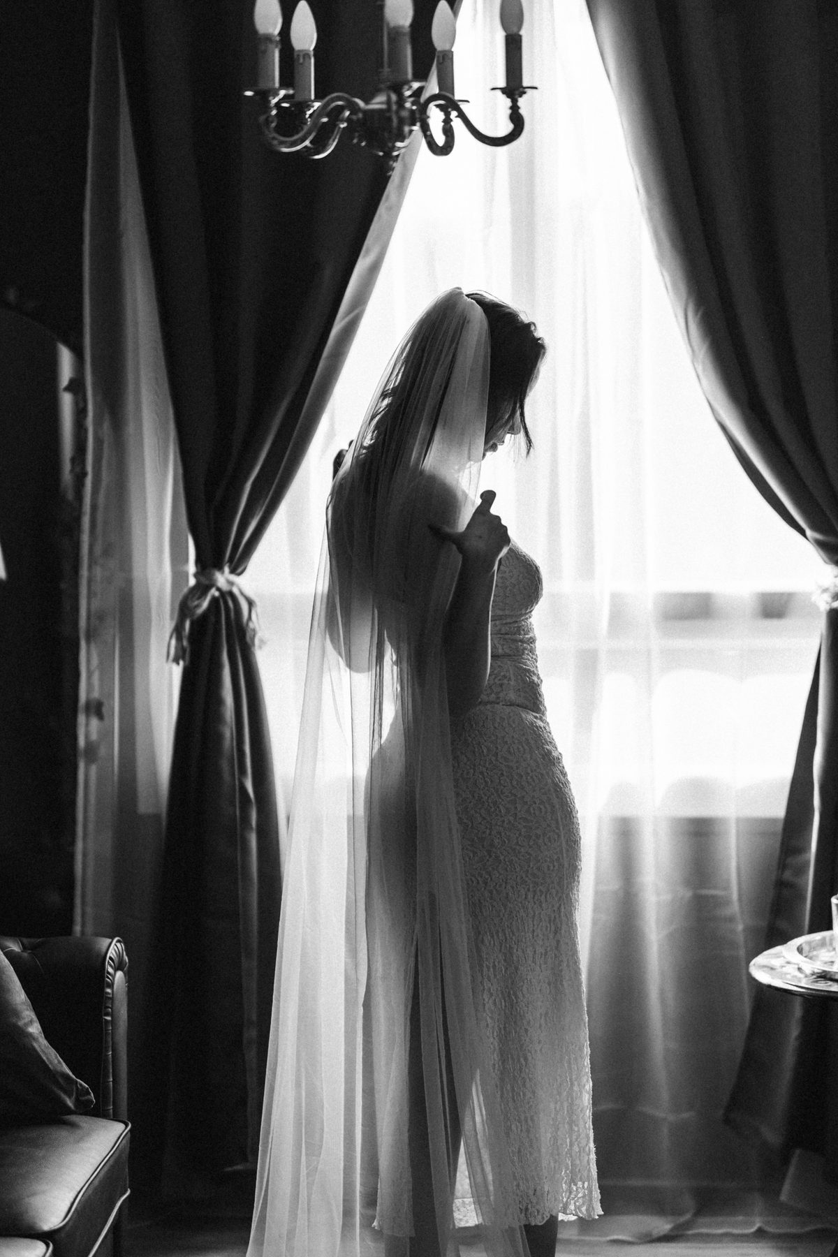 Mariée en voile devant une fenêtre, silhouette à contre-jour en noir et blanc